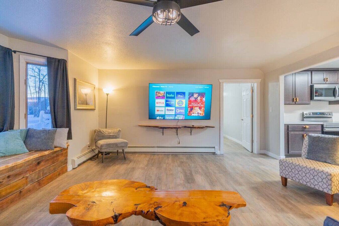 Un soggiorno moderno con un tavolino in legno, un divano, una TV a parete e una ventola a soffitto.