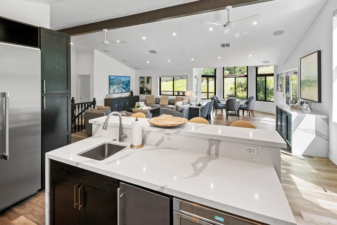 Una cocina moderna con una isla central, electrodomésticos integrados y un comedor con vistas.