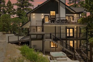 A multi-story house with a balcony, outdoor seating, and a hot tub.
