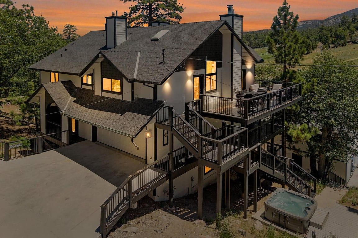 Een tweelaags huis met een balkon, een hottub en een terras.