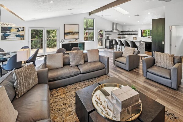 A spacious living room with a sofa set, a coffee table, and a dining area with a table and chairs.