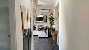 Una camera d'albergo moderna con un letto, una scrivania, una sedia, una pianta in vaso e uno specchio.