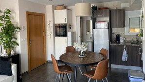 Una cucina moderna con mobili bianchi, forno integrato, microonde e frigorifero. C'è un tavolo da pranzo con sedie e un vaso di fiori.