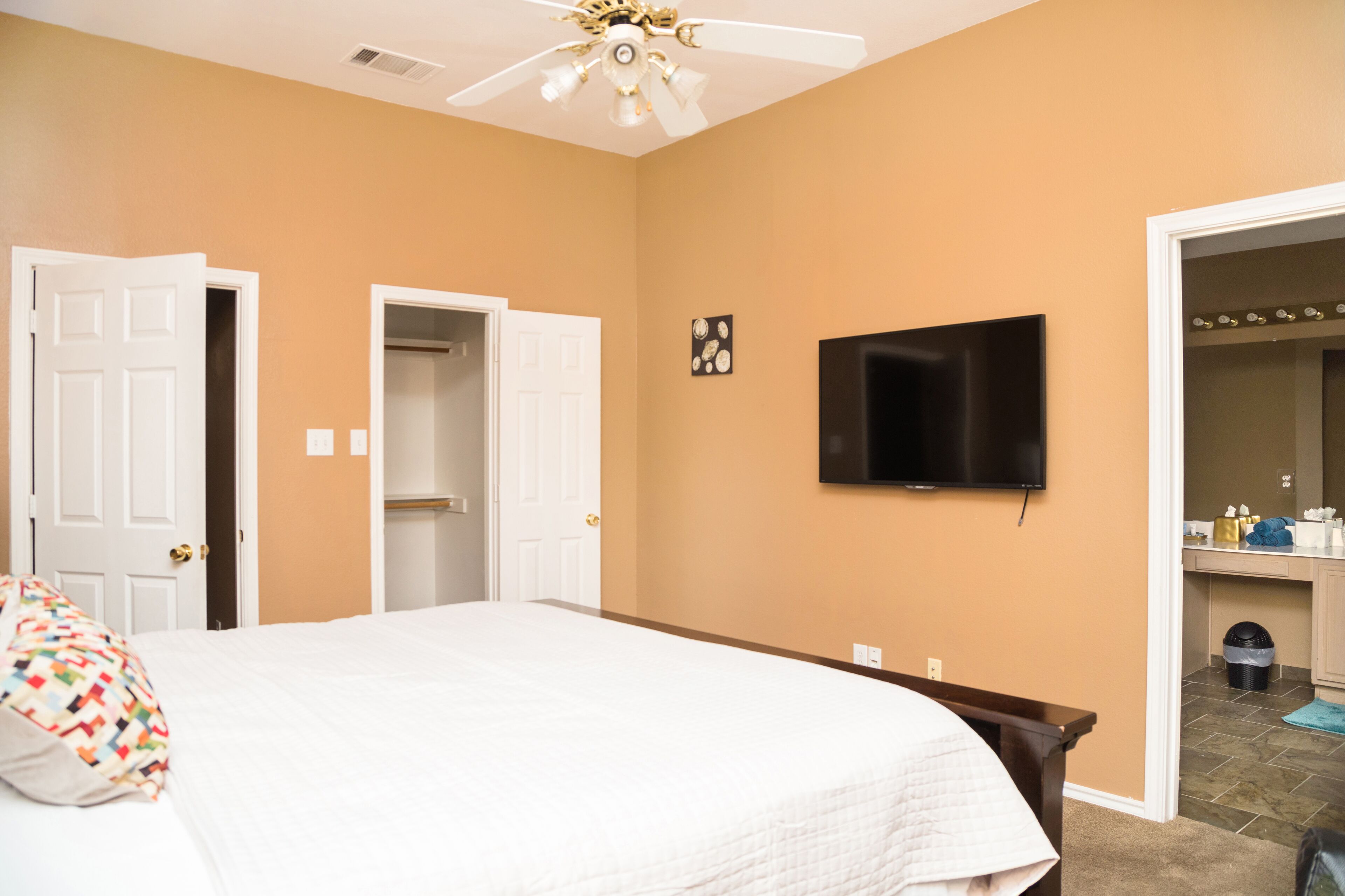 A bedroom with a bed, a TV mounted on the wall, and a closet.