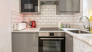 Una cucina compatta con forno a microonde, tostapane, bollitore e lavastoviglie.