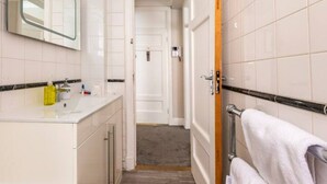Un bagno con lavandino bianco, specchio e portasciugamani.