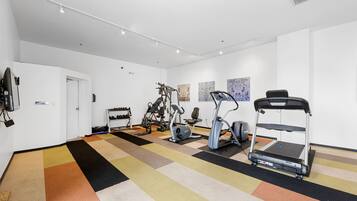 A gym with various exercise equipment, a patterned carpet, and white walls.
