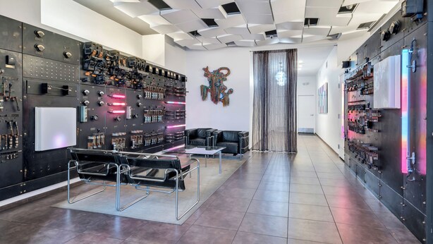 A modern hotel lobby with a checkered ceiling, a large wall of control panels, a black leather sofa, and a glass coffee table. - Modern 1BR Downtown condo with rooftop gym & skyline views. King bed, Wi-Fi, walk to Canal & FQ (New Orleans)