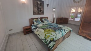 Un dormitorio con cama, mesitas de noche, un armario de madera y un cuadro de un elefante colgado en la pared.