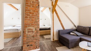A modern room with a brick wall, wooden beams, a grey sofa, and a bed with a wooden headboard. - Zur Altstadt 3 - modern apartment just a few minutes' walk from the historic old town (Monschau)