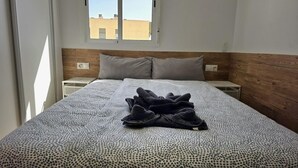 Ein Schlafzimmer mit einem Bett, zwei Nachttischen, einem Fenster und Blick auf Gebäude.