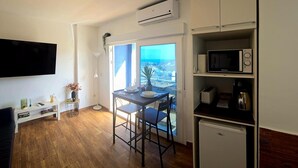 Ein kompakter Wohnbereich mit Essplatz, Küchenzeile und großem Fenster mit Aussicht.