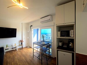 A compact living space with a dining area, kitchenette, and a large window offering a view. - Air-conditioned apartment near the beach with Wi-Fi (Torremolinos)