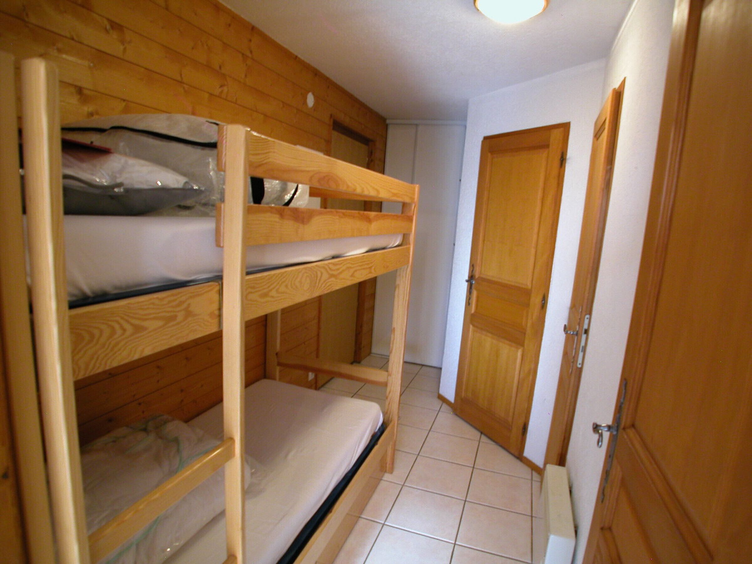 A bunk bed room with wooden walls and a tiled floor.