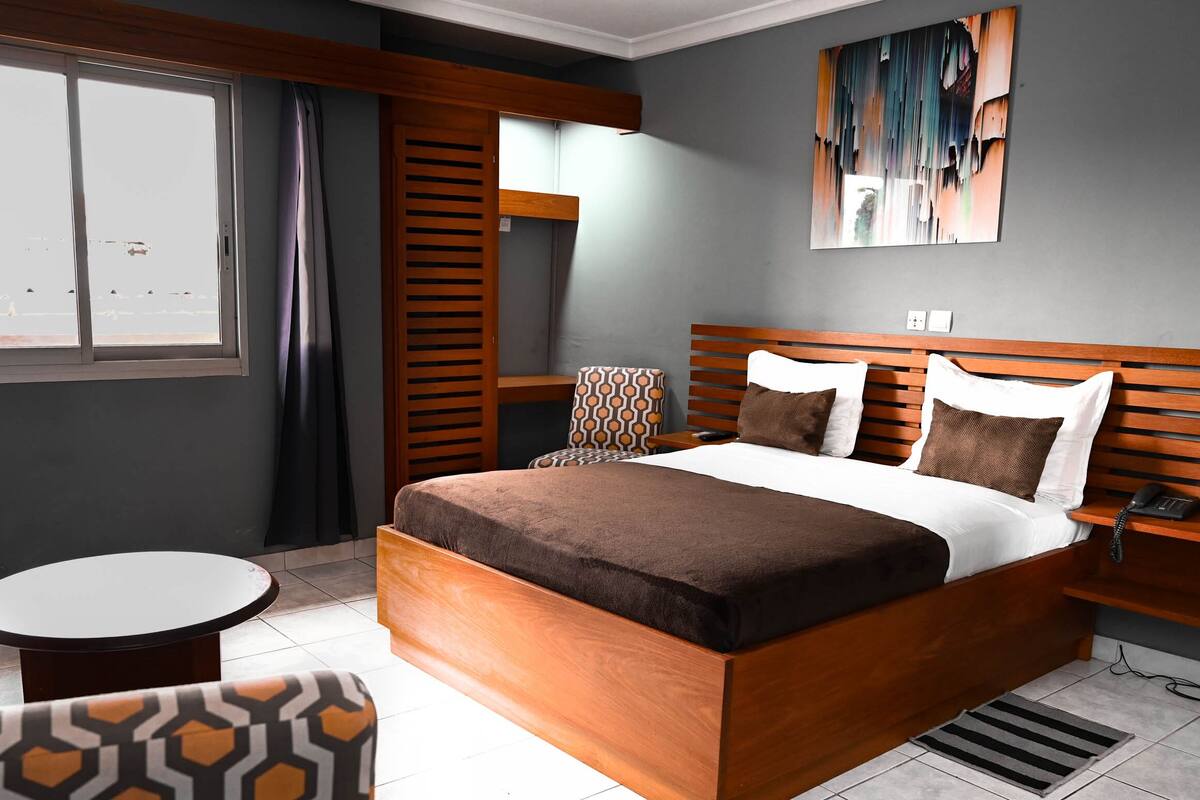 A modern hotel room with a wooden bed, a round table, and a chair.