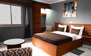 A modern hotel room with a wooden bed, a round table, and a chair. - HOTEL ASTORIA (Douala)