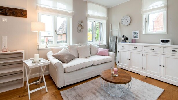 Een moderne woonkamer met een witte bank, een ronde salontafel en een witte kast.