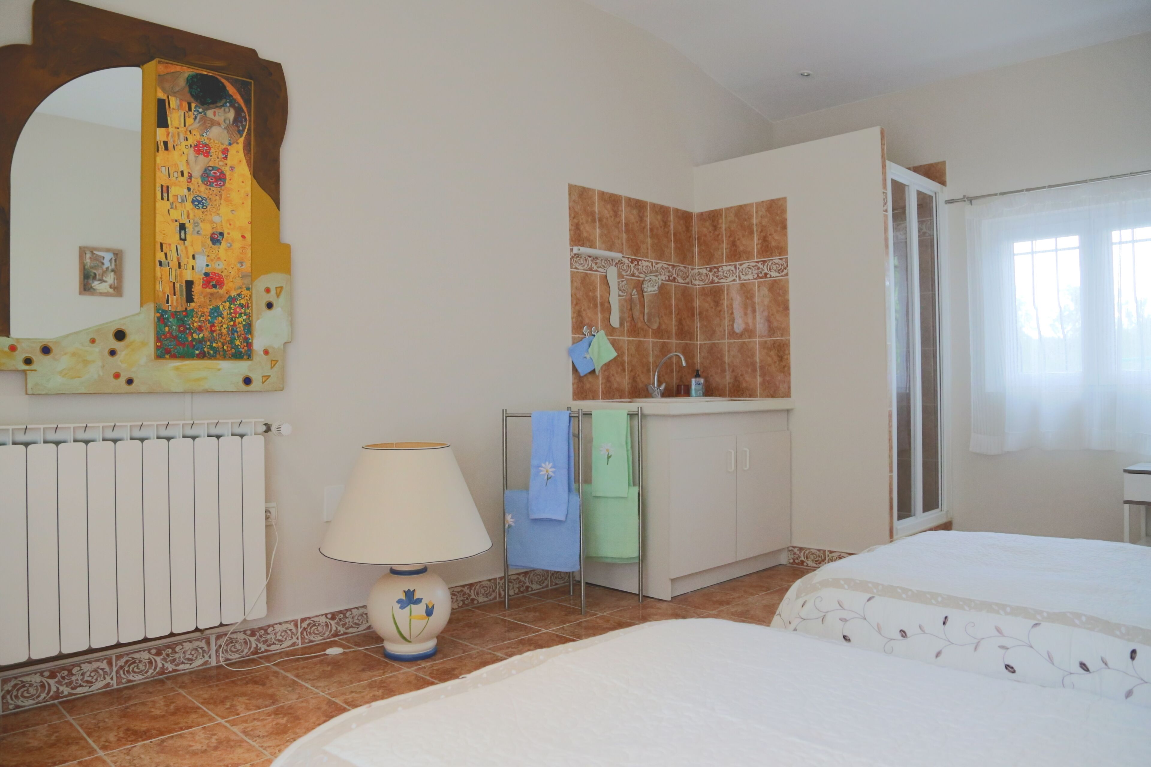 Een hotelkamer met een grote spiegel, een radiator, een wastafel, een handdoekrek en een bed.