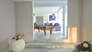 Un salon moderne avec une table de billard, un canapé et un escalier menant à une autre pièce.