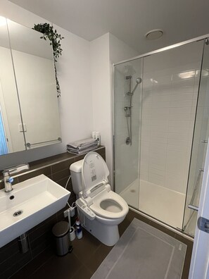 A modern bathroom with a white sink, toilet, and glass shower enclosure.