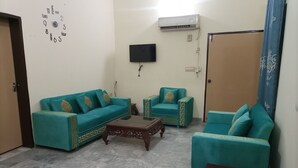 Ein Wohnzimmer mit einer Couch, zwei Sesseln, einem Couchtisch und einem flachbildfernseher an der Wand.