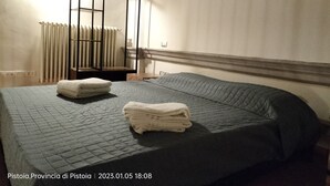 A hotel room with a bed, a radiator, and a window with curtains. - Apartment with terrace, parking A/C, Wi-Fi, in the old town (Pistoia)