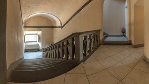 A grand staircase with a black handrail and white balusters, leading to a landing with a view of a balcony. - Apartment with terrace, parking A/C, Wi-Fi, in the old town (Pistoia)