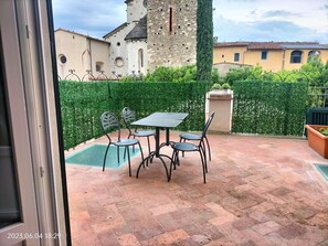 A patio with a table and chairs, a small pool, and a hedge.