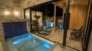 Relax by the pool surrounded by lush gardens and a mosaic tile wall.