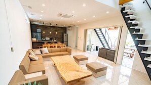 En rummelig opholdsstue med sofaarrangement, et træsofa bord og en trappe med moderne design.