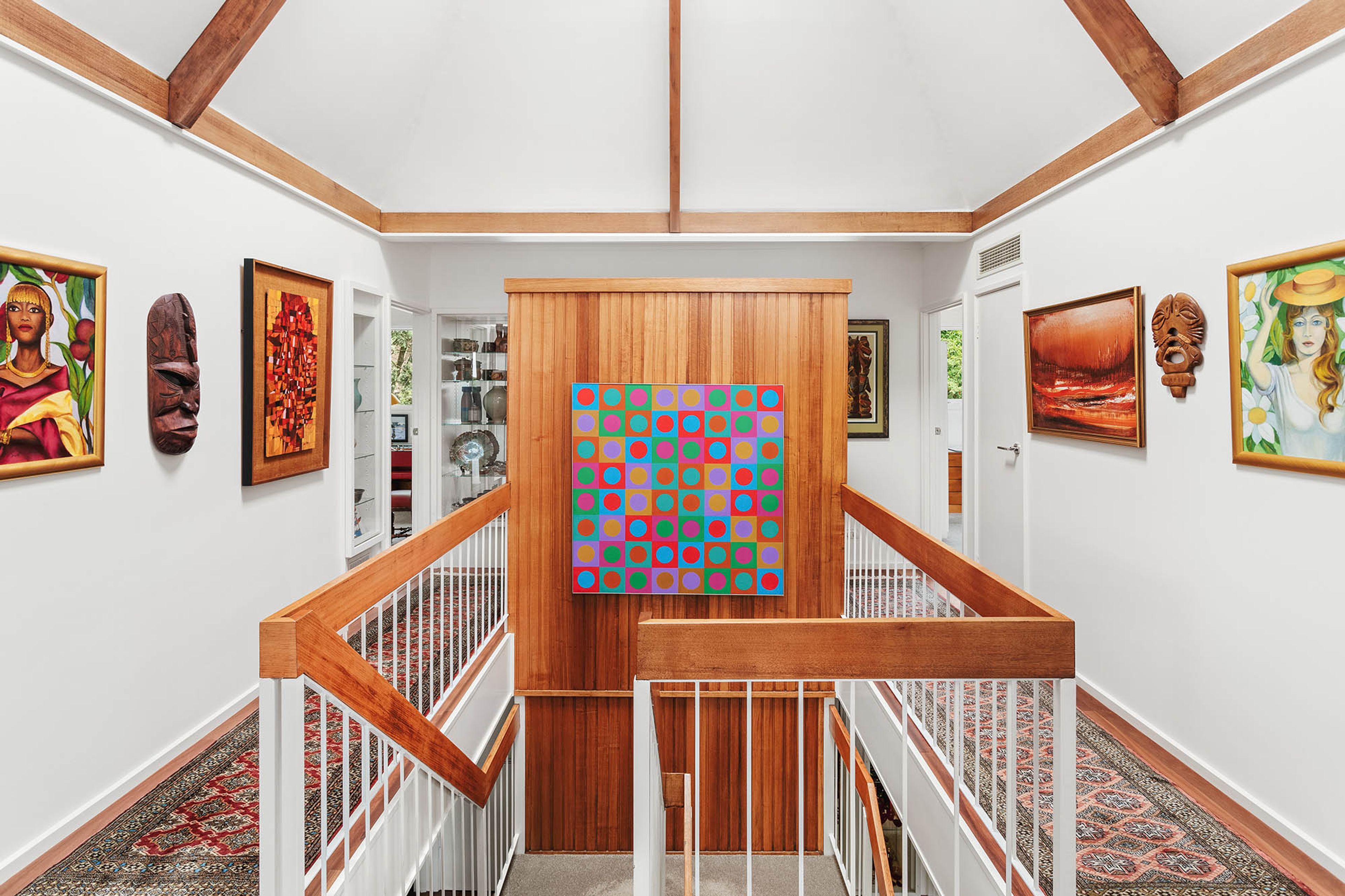 A staircase with a wooden handrail and a colorful pop art piece on the wall.