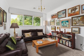 A living room with a sofa, coffee table, bookshelves, and artwork on the walls. - That 70s House in Mount Waverley (Mount Waverley)