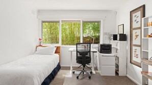 A bedroom with a bed, desk, chair, and a window with a view of greenery. - That 70s House in Mount Waverley (Mount Waverley)