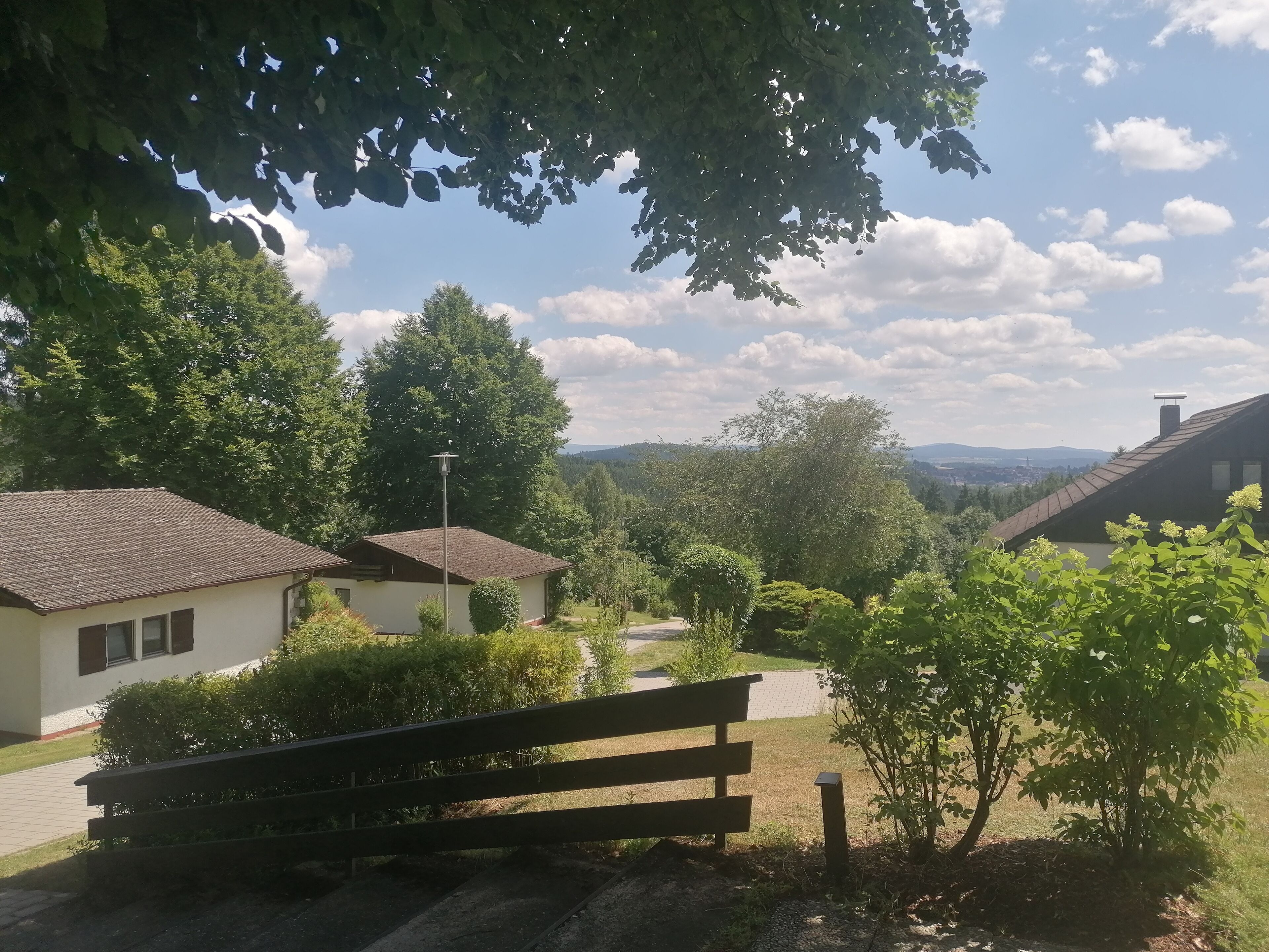 A residential area with houses, a bench, and a clear view of the surrounding landscape.