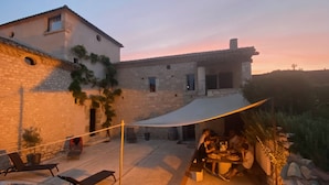 Un edificio de piedra con un patio, mobiliario exterior y un espacio cubierto para comer.
