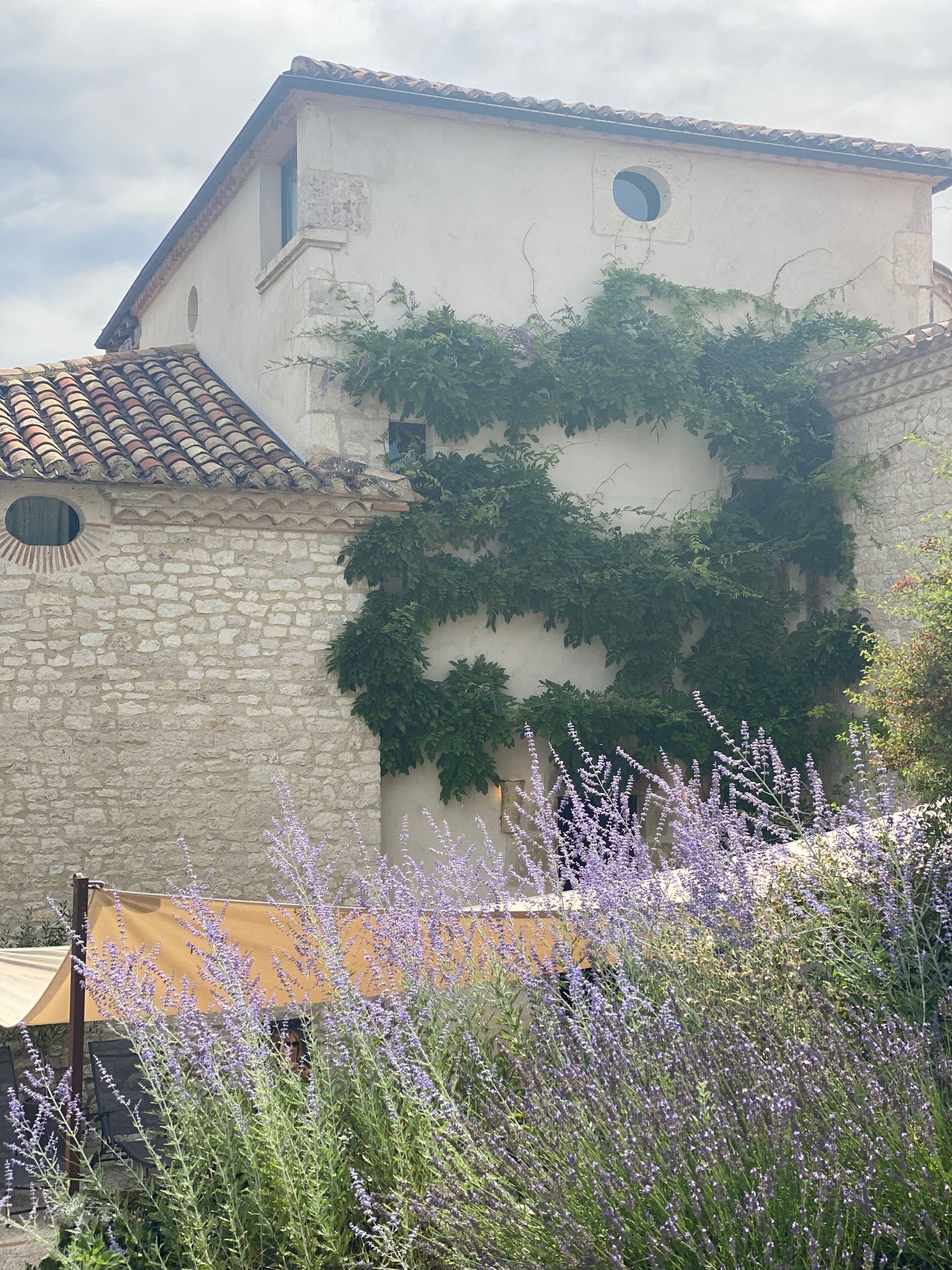A building with stone walls and a tiled roof, featuring a small window and a circular window.
