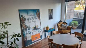 A cozy dining area with a round table and wooden chairs, a blue side table with a plant, and a large poster on the wall. - Cute, cozy country escape in a new unit close to cherry and strawberry orchards (Maddingley)