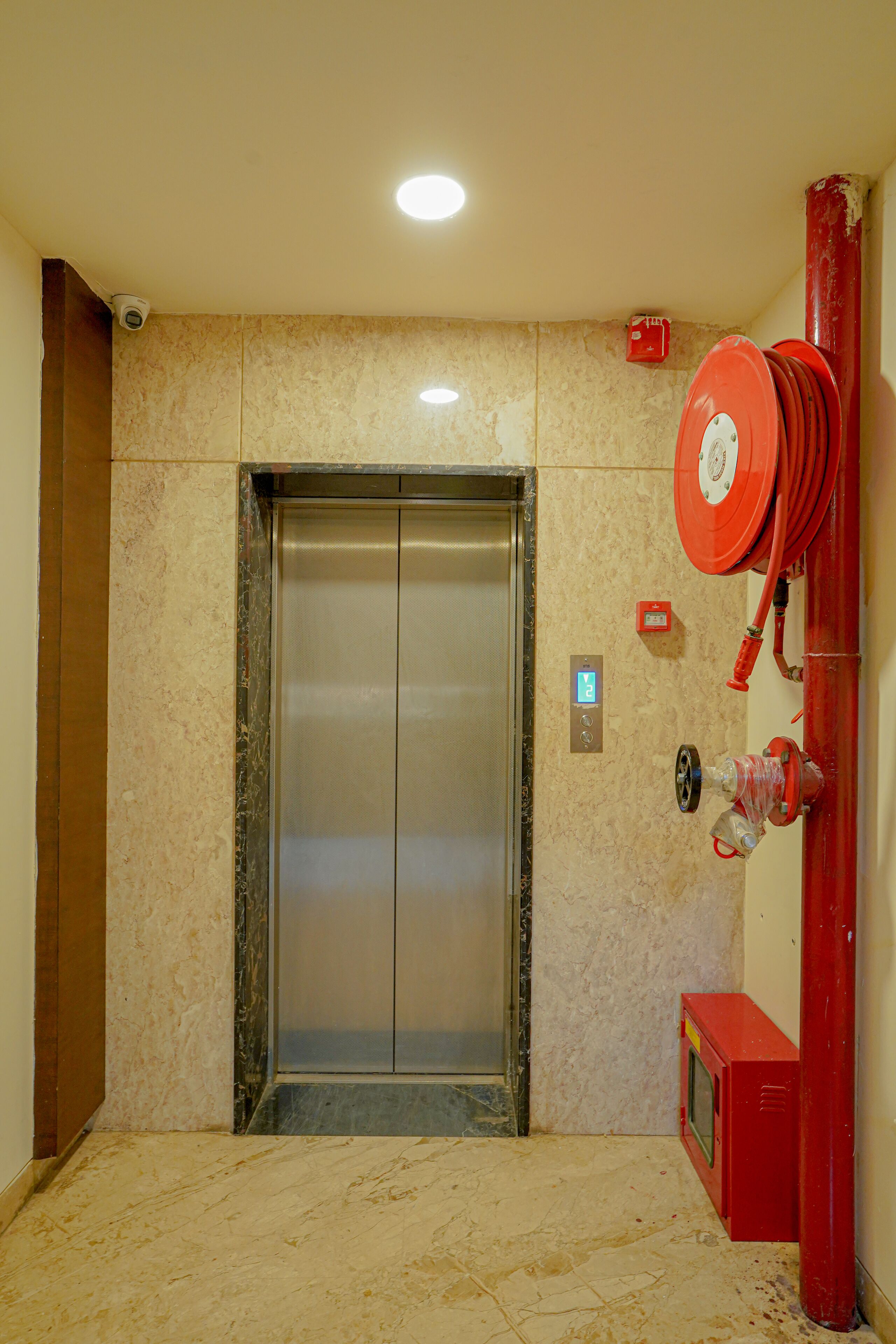 An elevator with a control panel and a fire hose reel mounted on the wall.