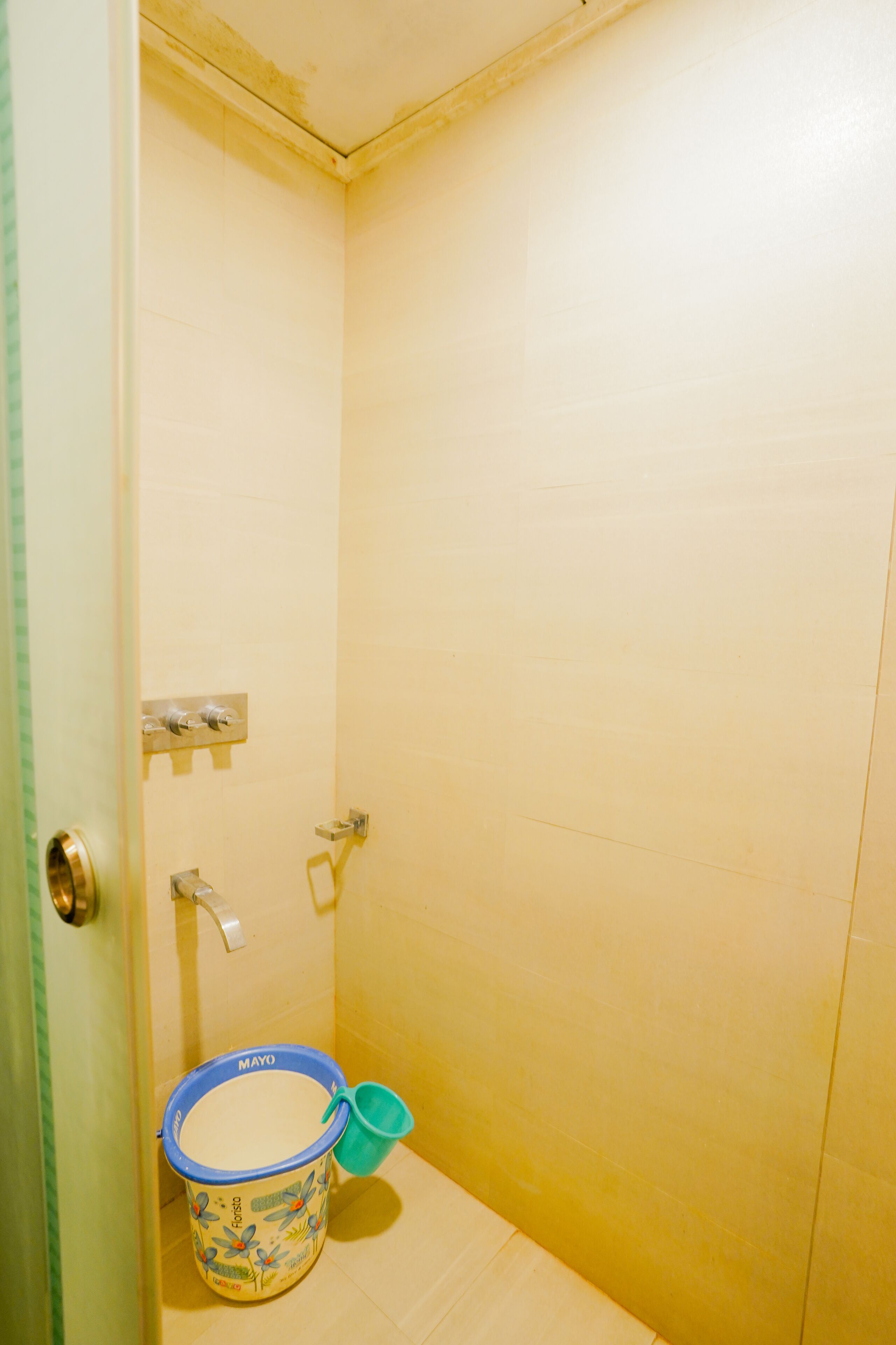 Ein kleines Badezimmer mit Dusche, Toilette und Eimer.