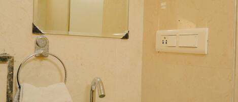 A bathroom with a sink, mirror, towel rack, and a wall-mounted electrical outlet.
