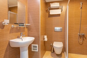 Un baño moderno con lavamanos, inodoro y ducha.