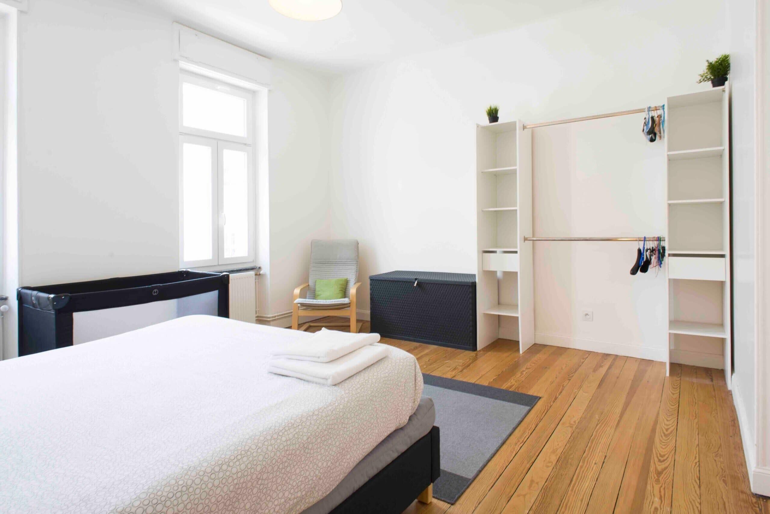 Een slaapkamer met een bed, een stoel, een kledingkast en een radiator.