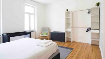Een slaapkamer met een bed, een stoel, een kledingkast en een radiator.