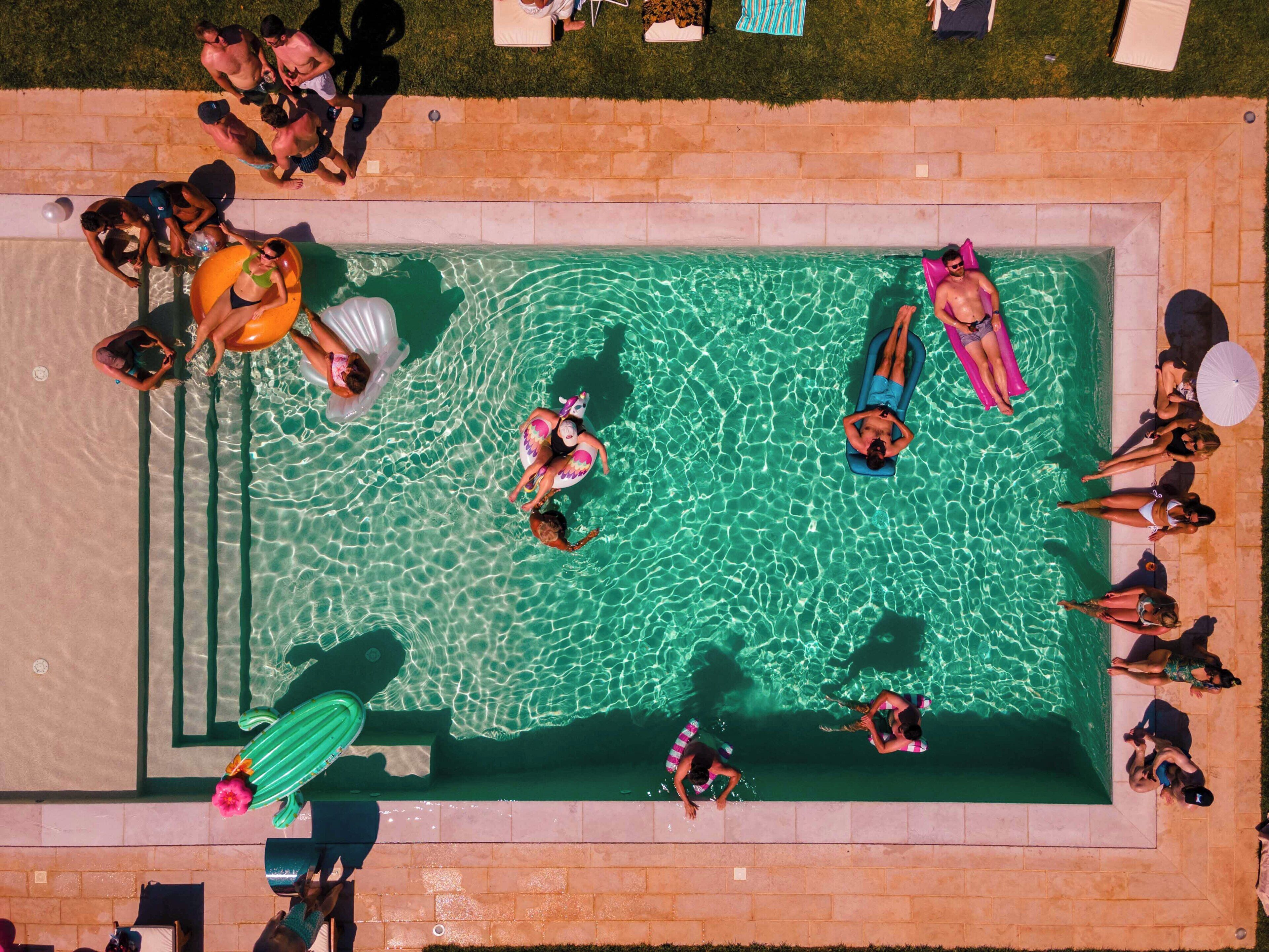 An aerial view of a swimming pool with people sunbathing and swimming.