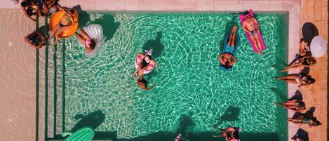 An aerial view of a swimming pool with people sunbathing and swimming.