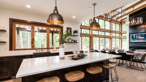 A modern kitchen with a large island, bar stools, and pendant lighting. - Stunning modern luxury in the Cascade Mountains (Cle Elum)