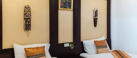 A hotel room with two beds, each with white linens and brown decorative pillows. There are wooden headboards and a small framed picture on the wall.