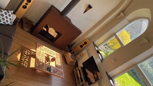 A modern living room with a wooden accent wall, a large window with a view of greenery, and a built-in speaker system. - A peaceful night's sleep at La Chapelle (Rochefort)