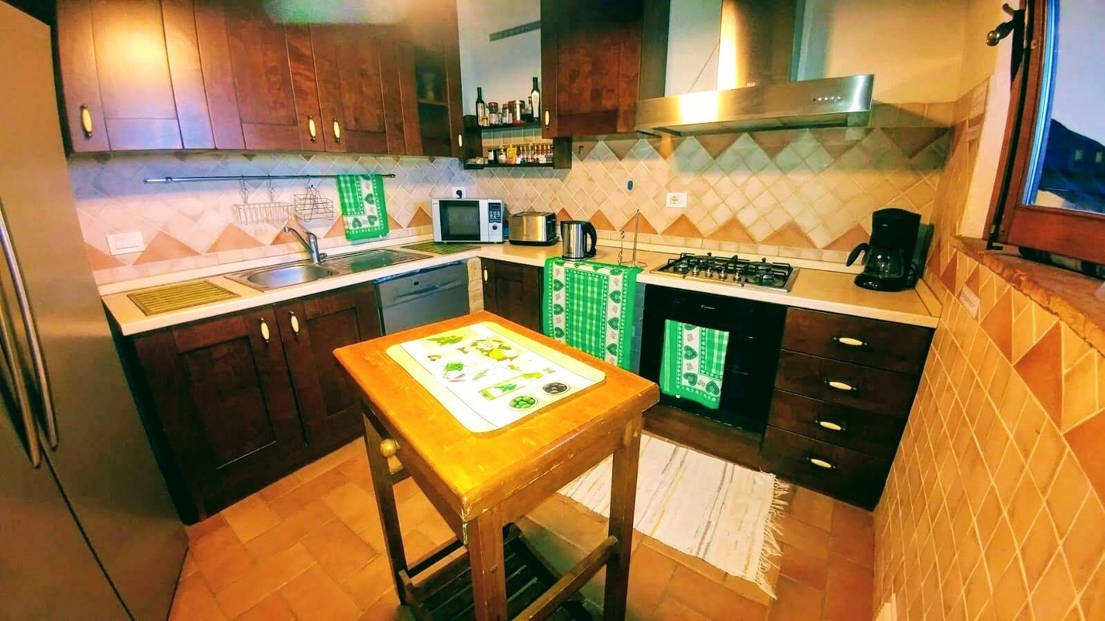 A compact kitchen with dark wooden cabinets, a gas stove, a microwave, and a sink.