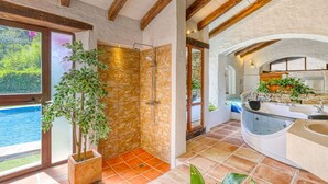 Un baño con ducha de piedra, bañera y lavamanos.